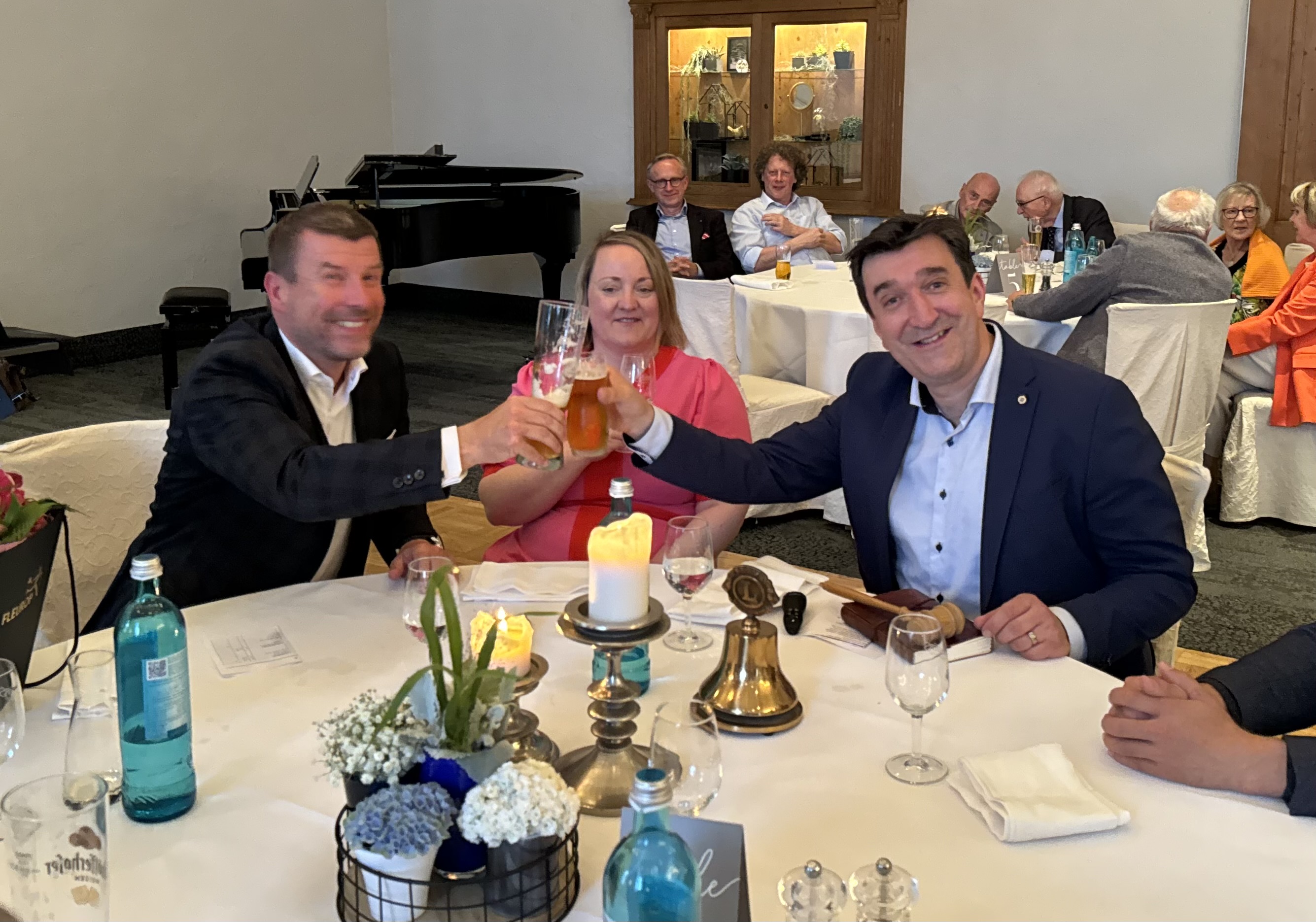 Der alte und neue Präsident stoßen mit einem Glas Bier an. Dazwischen sitzt Jörg Bachmanns Frau