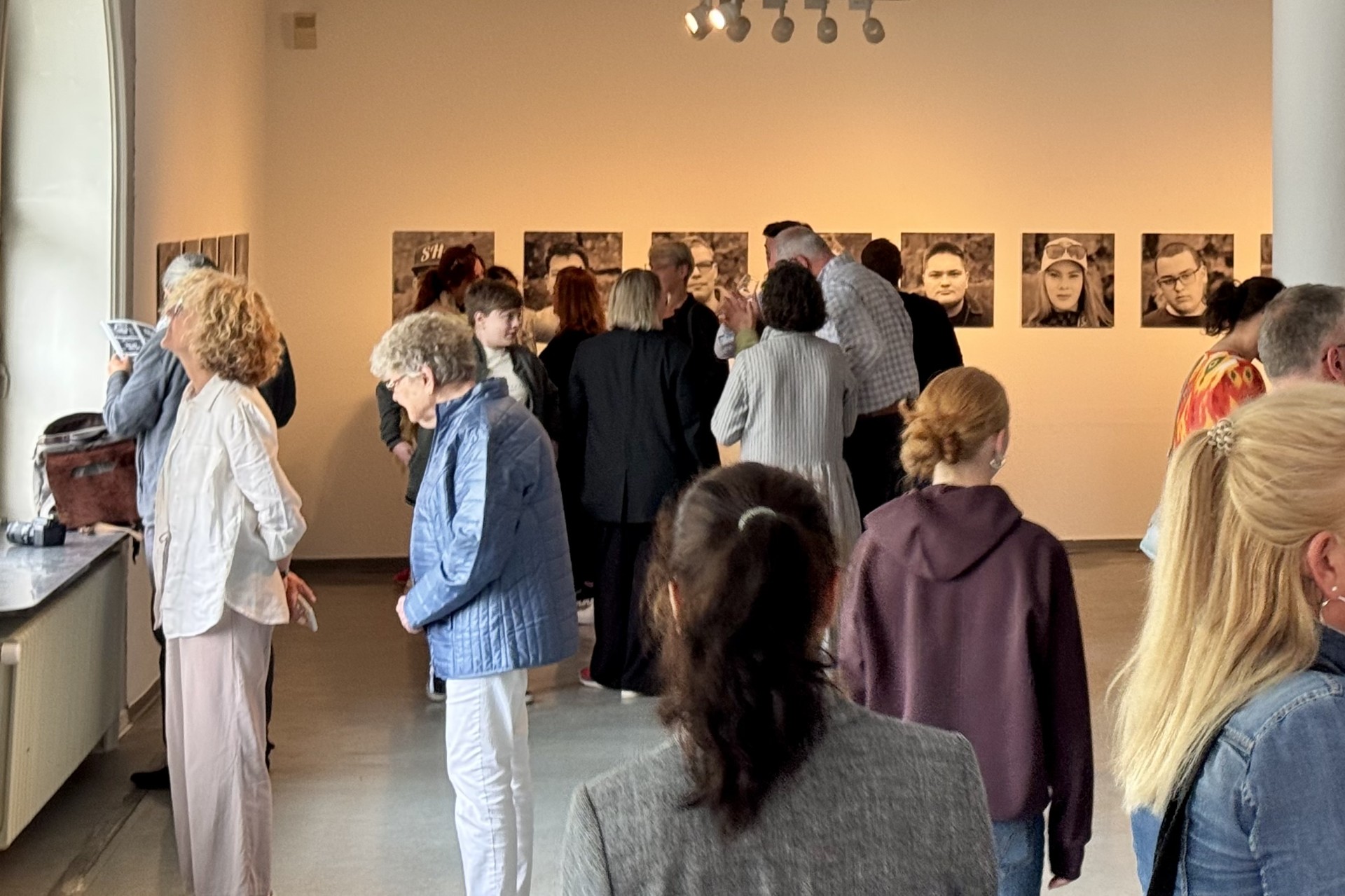 Besucher der Ausstellungseröffnung betrachten die Bilder im Museum