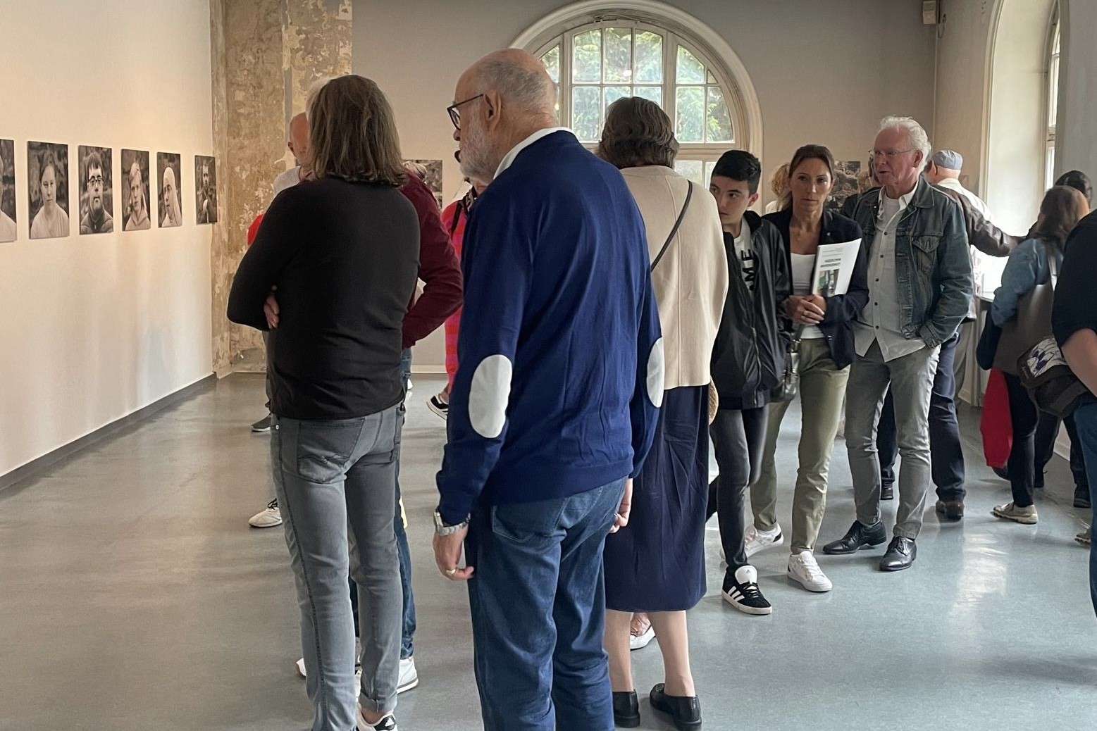 Besucher der Ausstellungseröffnung betrachten die Bilder im Museum