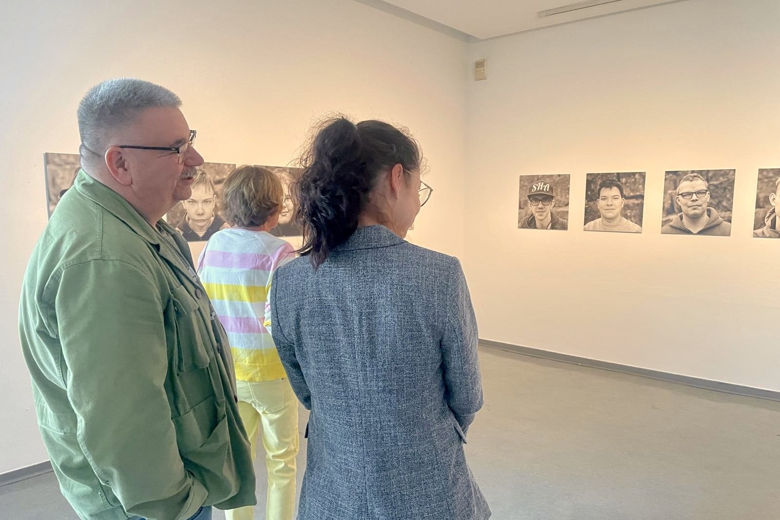 Der Fotograf und Besucher der Ausstellungseröffnung betrachten die Bilder im Museum