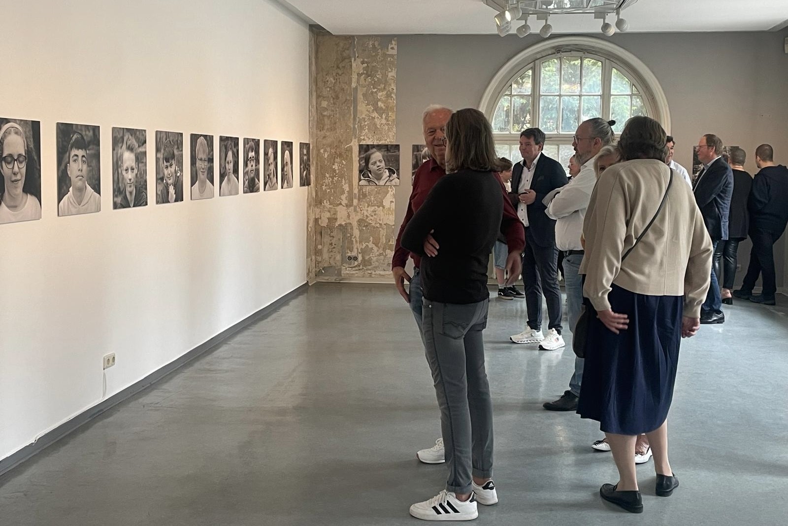 Besucher der Ausstellungseröffnung betrachten die Bilder im Museum