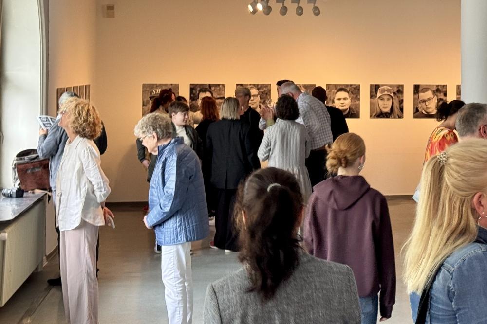 Besucher der Ausstellungseröffnung betrachten die Bilder im Museum